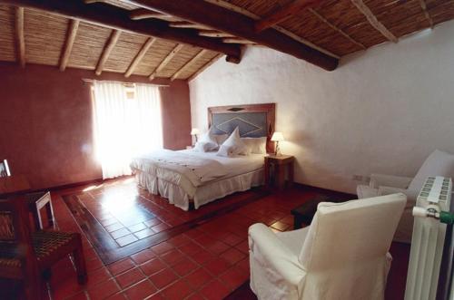 普尔马马尔卡Del Amauta Hosteria的一间卧室,卧室内配有一张床和椅子