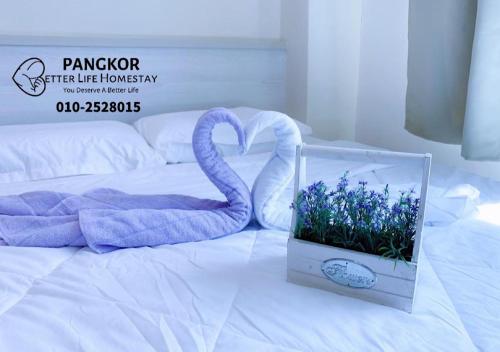 邦咯Pangkor Pasir Bogak Apartment 2Rooms 2Bathrooms near beach 6pax FREE WIFI的床上的盒子,上面有天鹅和鲜花