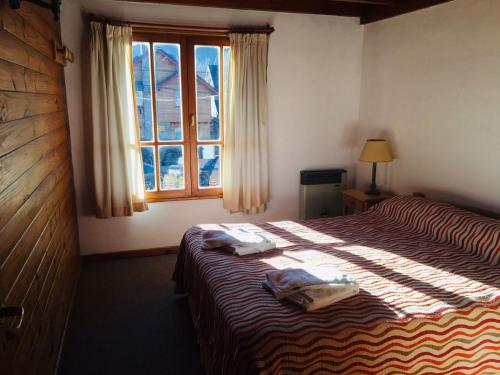 圣马丁德洛斯Cabañas Chapelco的一间卧室配有一张床,上面有两条毛巾