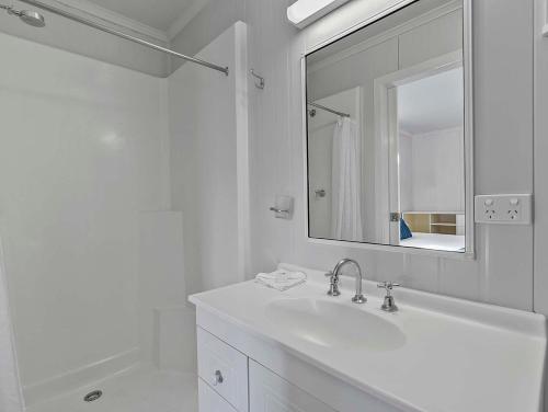 鲍恩皇后海滩旅游村酒店的白色的浴室设有水槽和镜子