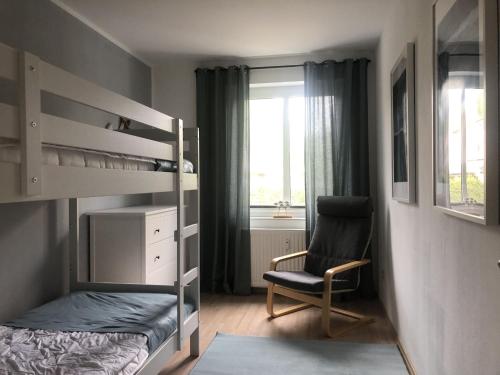 博尔滕哈根Bright Apartment in Boltenhagen near the Sea的一间卧室配有双层床和椅子