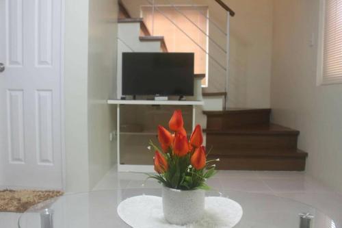 八打雁Pontefino Prime Townhouse 4BR with Wifi & Pool的客厅里的一个花瓶,上面有红色的花朵