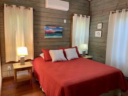 桑迪湾Phoenix House的一间卧室配有一张红色的床和两盏灯