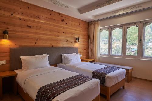 廷布The Willows Hotel, Bhutan的配有木墙和窗户的客房内的两张床