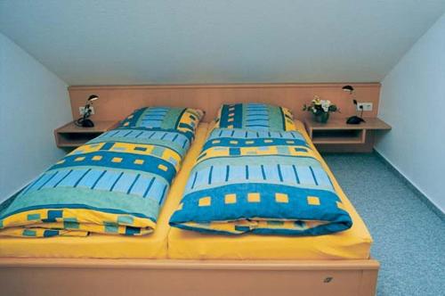 诺德奈Dünenwind Dünenwind 04的一间卧室配有3张带蓝色和黄色枕头的床