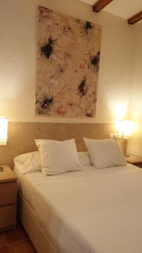贝赫尔-德拉弗龙特拉Las casas de Colinas的一张铺有白色床单的床和墙上的绘画