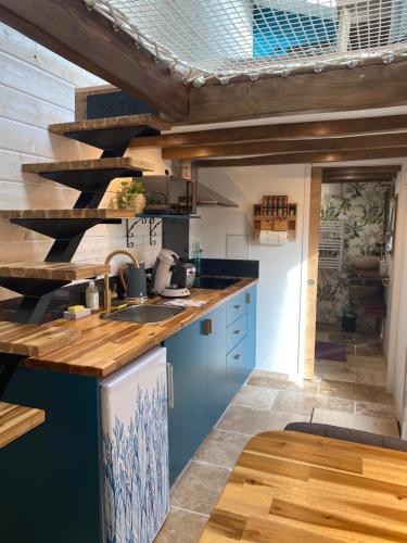 圣艾尼昂La Tiny Blue - maison insolite pour 2 - sans Tv的厨房配有蓝色橱柜和木制天花板