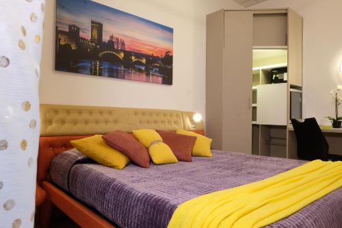 维罗纳LeNotti Verona的一间卧室配有一张带紫色和黄色枕头的床