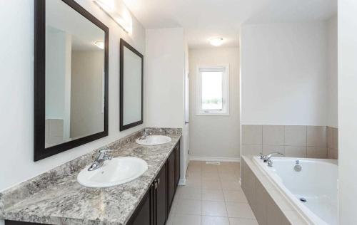 索罗尔德Brand New Big House in Niagara Region的浴室设有2个水槽、浴缸和镜子