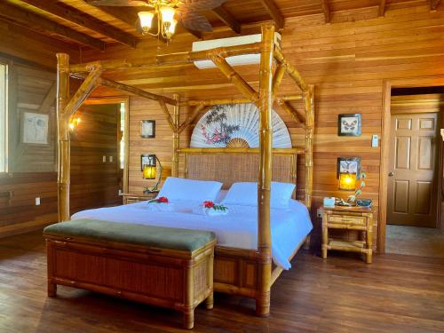 Teakettle VillageDream Valley Belize的木制客房内的一间卧室配有一张天蓬床