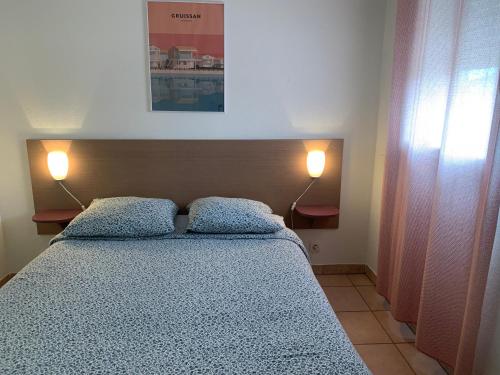 格吕桑T2 Les jardins Gruissan的一间卧室配有一张带两个枕头和两个灯的床。