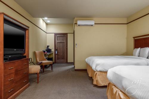 哈里森Hotel Seville的酒店客房设有两张床和一台平面电视。