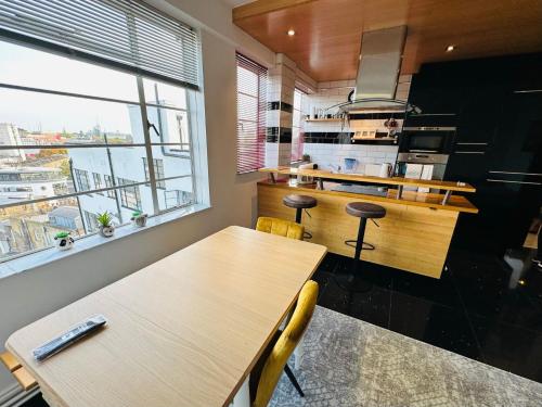 伦敦Beautiful Quality Apartment in Camden Town的一间带木桌和大窗户的厨房