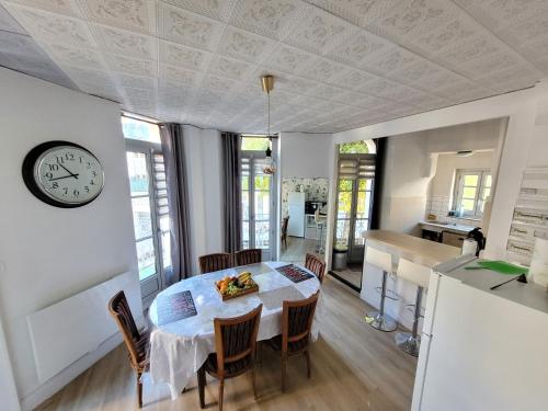 巴涅尔-德吕雄Bel Appartement Bagneres De Luchon Centre的厨房以及带桌子和时钟的用餐室。