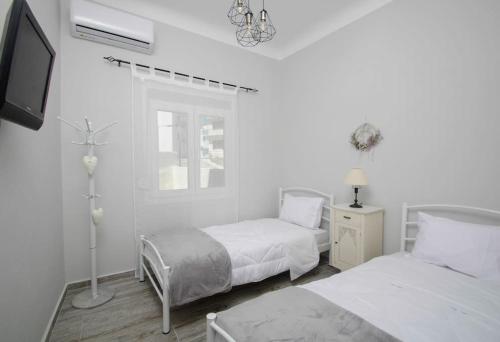埃尔莫波利斯La Rosa的一间白色卧室,配有两张床和电视