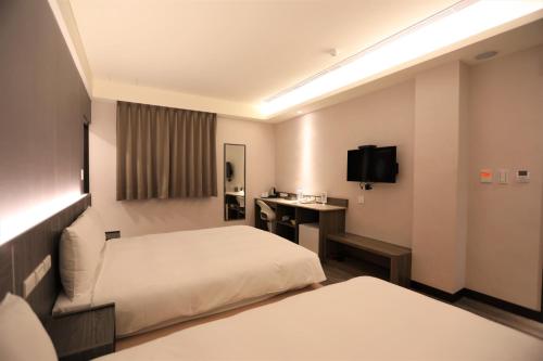 台北城美行旅的酒店客房配有两张床和一张书桌