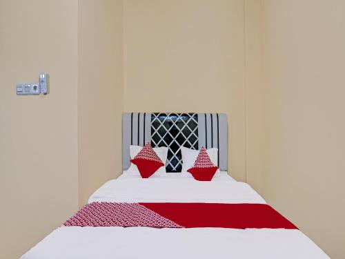 北干巴鲁OYO 91835 Djasur Kost的一间卧室配有一张带红色枕头的床