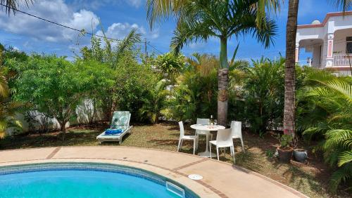 康隆尼角Tropical Palms apartment Mauritius的池畔露台配有桌椅