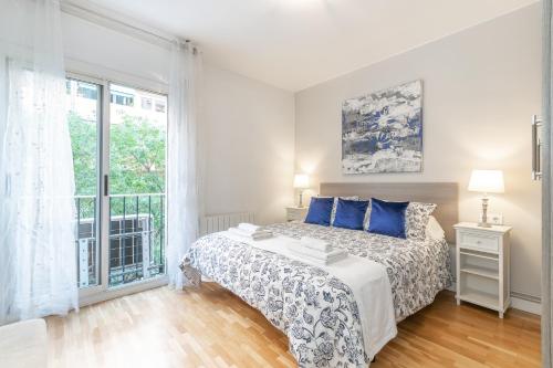 巴塞罗那Elegance Barcelona Rentals的一间卧室配有一张带蓝色枕头的床和一扇窗户。