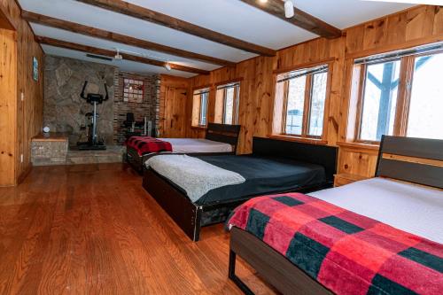 Algonquin HighlandsPine Springs Retreat with Hot Tub Steam Room Lake Kushog的带木墙和窗户的三张床的客房