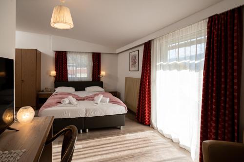 西兰德罗祖尔林德帕克酒店的一间卧室配有一张带红色窗帘的床和一张桌子