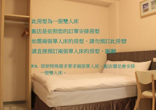 高雄六合日丽饭店的卧室配有一张床铺,墙上挂着中国书写