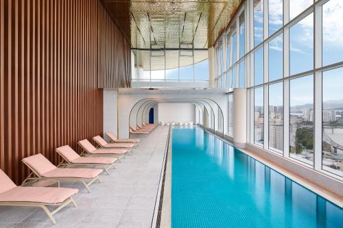首尔Hotel Naru Seoul MGallery Ambassador的一座带椅子和窗户的建筑中的游泳池