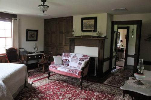 埃尔金斯Upstairs Historic 1 Bedroom 1 Bath Suite with Mini-Kitchen, Porch & River Views的一间卧室配有一张床、一把椅子和一个壁炉