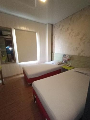 雅加达Hotel Aleander的酒店客房设有两张床和窗户。