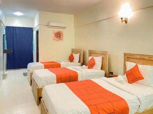 卡拉奇GOHO Rooms 10th Commercial的酒店客房带两张床,橙色和白色