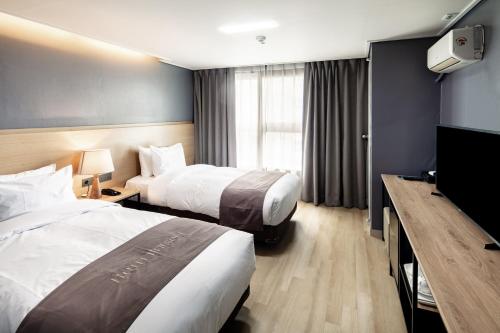 首尔Hotel Bernoui Seoul的酒店客房设有两张床和一台平面电视。