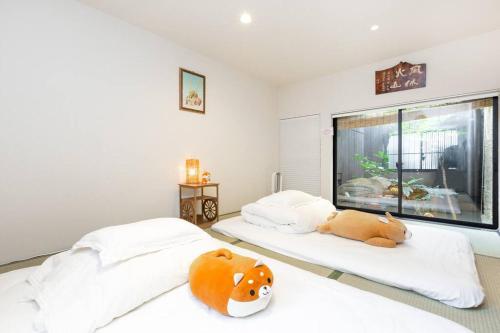 京都ゲストハウス至の宿 Shibainu-Themed Guesthouse的卧室内的两张床,里面放着动物