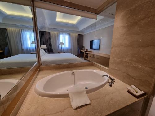 金海市松树林酒店的带浴缸和大镜子的浴室