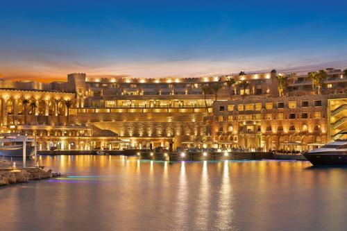 赫尔格达Pickalbatros Citadel Resort Sahl Hasheesh的一座在夜间水面上灯亮的大建筑