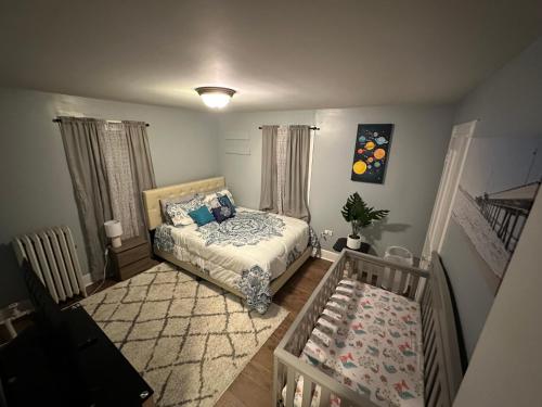 斯克兰顿4 bedrooms & 2 bathrooms “Dhanu’s place”的一间卧室配有一张床和一张婴儿床