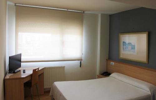 卢戈大都会卡利斯酒店的一间卧室配有一张床、一张书桌和一个窗户。