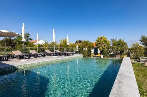 埃武拉QSF Agro Turismo Quinta da Sagrada Família的水边带桌椅的游泳池