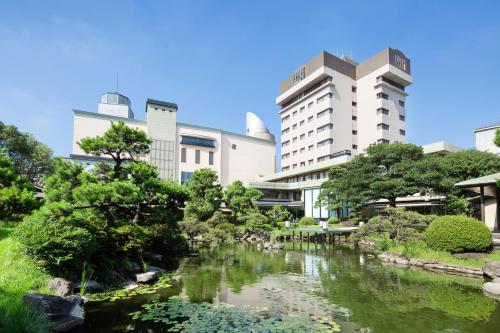 北九州Art Hotel Kokura New Tagawa的一座花园,位于一座河流建筑前