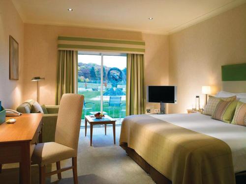 纽伯里唐宁谷高尔夫和SPA酒店的酒店客房设有一张大床、一张书桌和一张书桌。