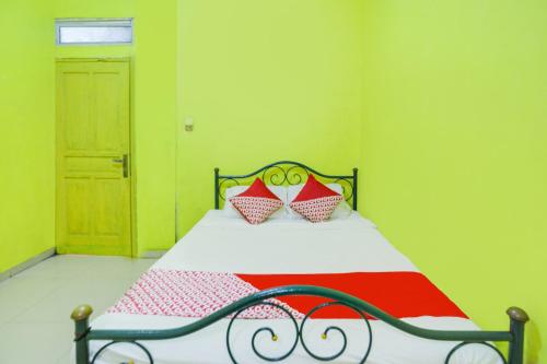 名古屋SPOT ON 91879 Emes Jaya Homestay的一间卧室设有一张红色和绿色的墙壁。