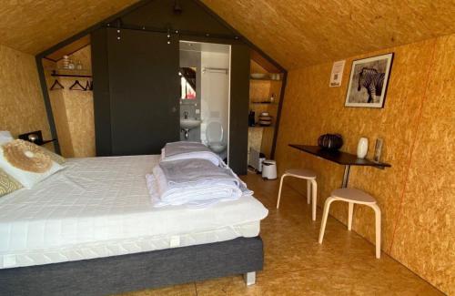 卡兰茨奥赫Tenthuisje in het groen, een suite met eigen badkamer的卧室配有一张床和一张桌子及椅子