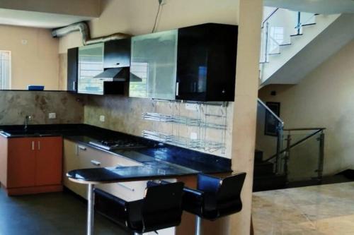 钦奈Private 4-BHK Villa with Swimming Pool, Wifi, BBQ的厨房设有黑色台面和楼梯