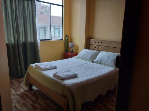 利马华琦公寓式酒店的一间卧室配有一张床,上面有两条毛巾
