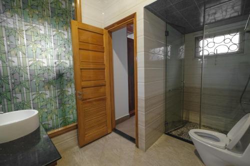 顺化Le Robinet Villa - a journey into Hue citadel soul的一间带卫生间和玻璃淋浴间的浴室