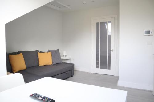 South NorwoodTwelve Thirty Serviced Apartments - 1 Croydon的客厅配有灰色的沙发和黄色的枕头。