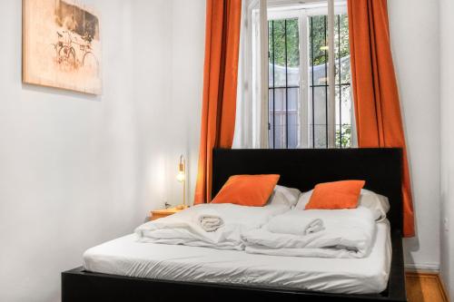 维也纳Chic Apartment - Very Central and Well Connected的一间卧室配有带橙色枕头的床和窗户。