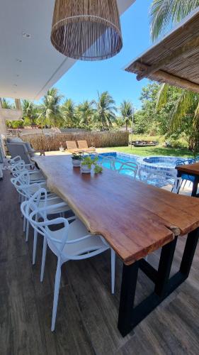 雅帕拉廷加Vila Leão do Norte的一张带白色椅子的木桌和游泳池