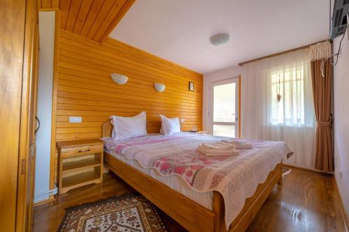 Poiana TeiuluiCabana TYF Dreptu - TYFTRAVEL SRL的一间卧室配有一张带木墙和窗户的床。