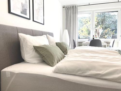 罗伊特林根Top-Apartment mit Parkplatz und Balkon的卧室内的一张带白色床单和枕头的床