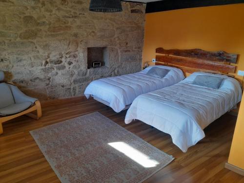 MasideO fogar da musiña的一间卧室设有两张床和石墙